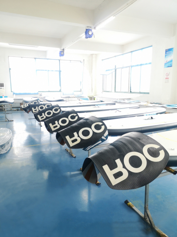 Certified OEM technicians handcrafting ROC-branded paddle boards with precision tooling in dedicated production zone